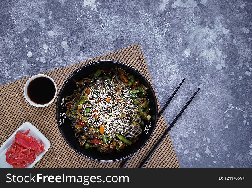 Buckwheat noodles with meat and vegetables, Asian wok on a gray