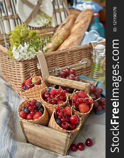 Selection of fresh berries displayed in cornets or ice cream cones in an old wooden box at a picnic with raspberries, strawberries, blueberries and cherries