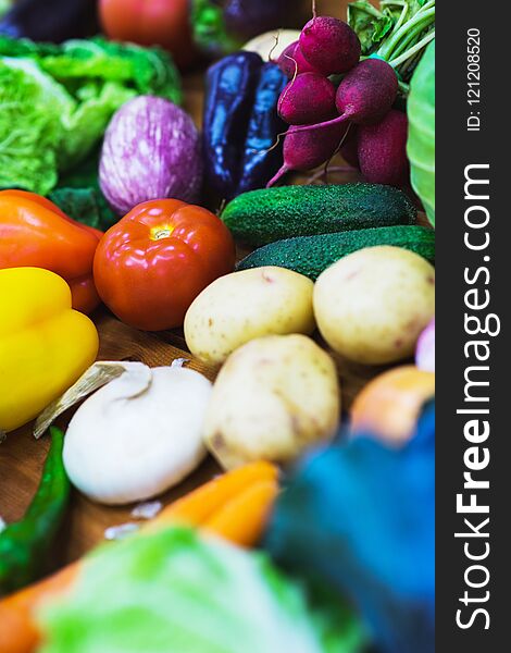 Vegetable assortment of different fresh vegetables on a wooden table top view. Ingredients for salads and light vegetarian snacks. Whole juicy fresh harvest from the farm. Soft focus. Vegetable assortment of different fresh vegetables on a wooden table top view. Ingredients for salads and light vegetarian snacks. Whole juicy fresh harvest from the farm. Soft focus.