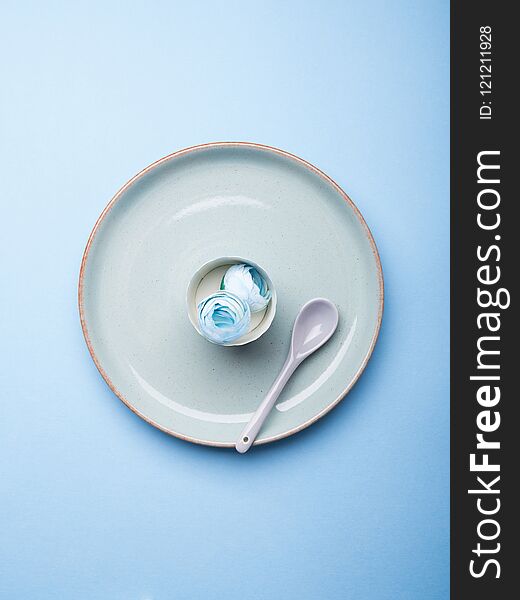 Blue pastel ceramic dish with flowers and spoon. Abstract food, tableware crockery, table setting monochrome concept
