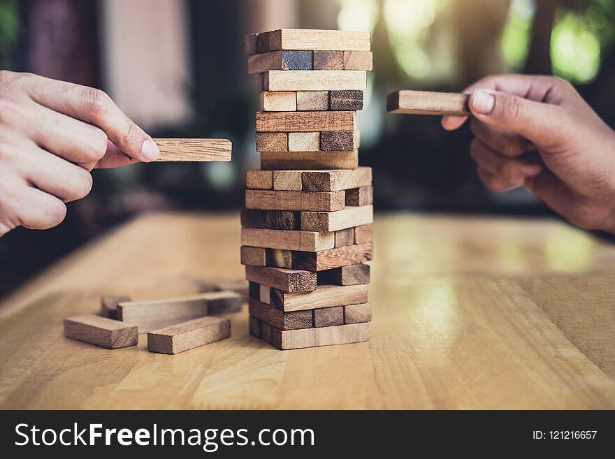 Hands of executive cooperation placing wood block on the tower, Collaborative management, Young intelligent businessman playing the wood game, Alternative risk concept, plan and strategy in business.