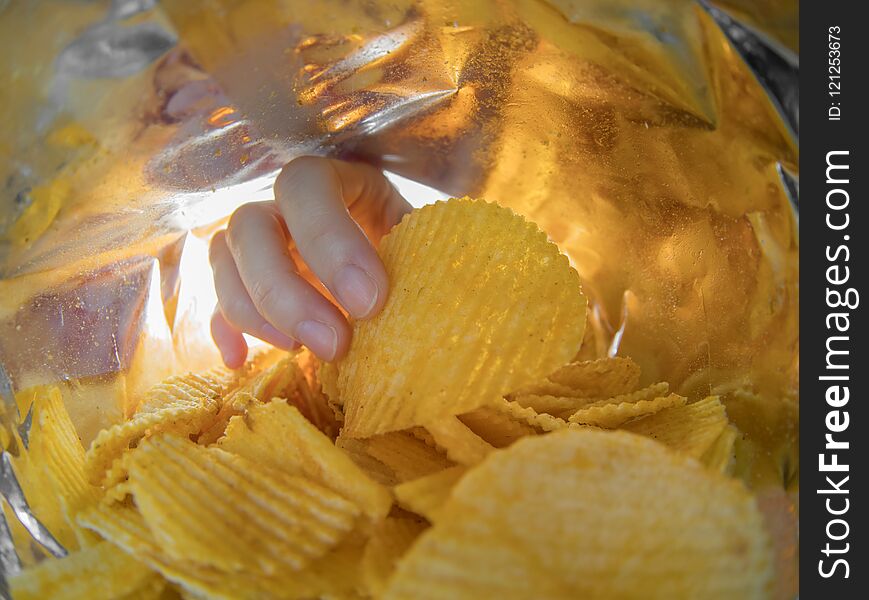 Hand taking potato chips inside the bag