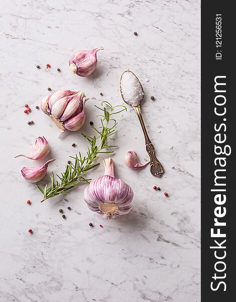 Garlic Cloves and Bulbs with rosemary salt and pepper on white marble board. Garlic Cloves and Bulbs with rosemary salt and pepper on white marble board.