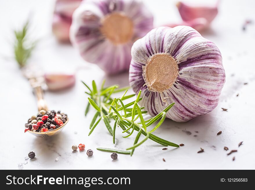 Garlic Cloves and Bulbs with rosemary salt and pepper on white marble board. Garlic Cloves and Bulbs with rosemary salt and pepper on white marble board.