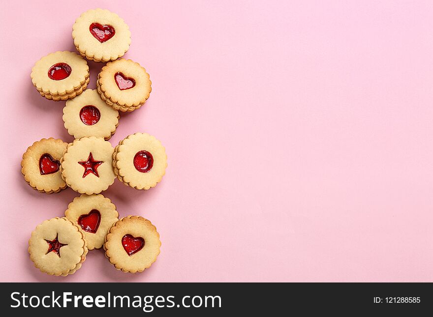 Traditional Christmas Linzer cookies with sweet jam on color background, top view