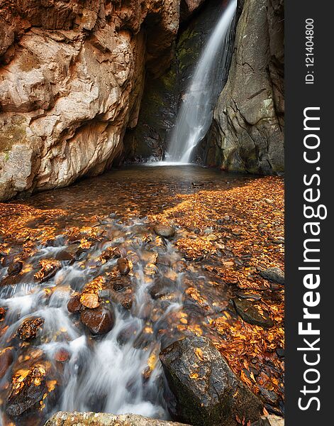 Beautiful river waterfall in autumn forest, a small waterfall part of Fotinski Waterfalls, Rhodope Mountains, Bulgaria