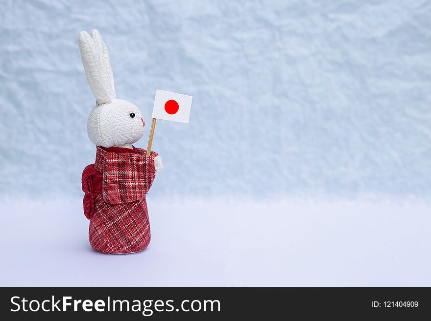 Fabric rabbit doll in red traditional Japanese dress holding Japan flag