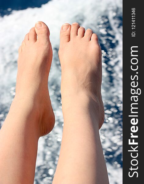 Vacation holidays. Women`s legs closeup on the background of sea water. Vertically framed shot.