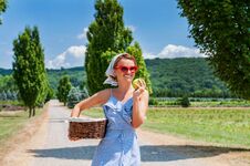Happy Woman In Dress With Wicker Basket Is Walking The Road In The Countryside Royalty Free Stock Photography