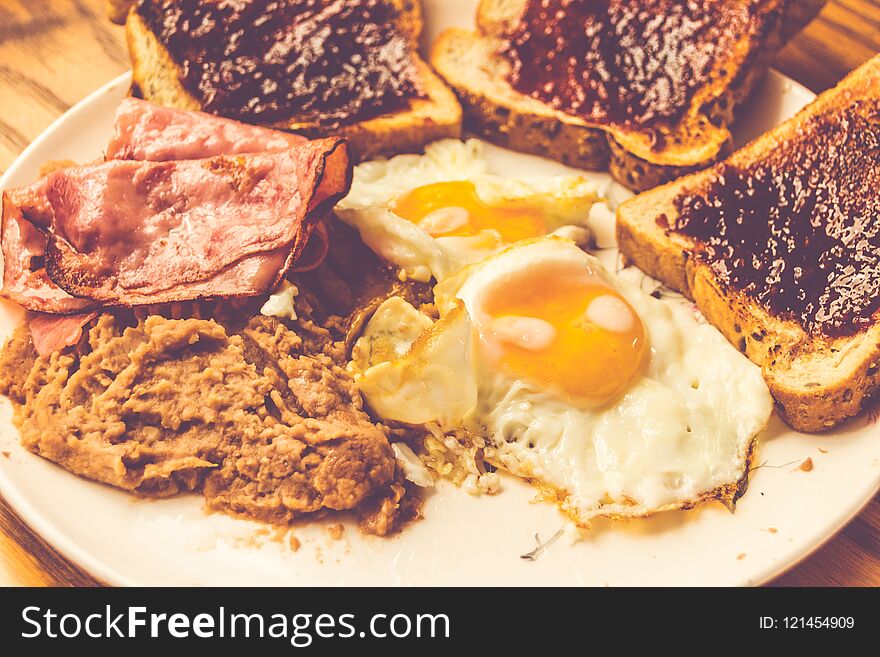 Photograph of a plate with fried eggs, beans, ham and bread. Photograph of a plate with fried eggs, beans, ham and bread
