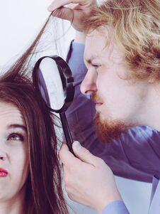 Man Looking At Woman Hair Through Magnifer Stock Image