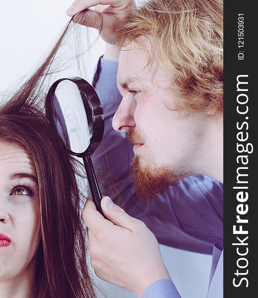 Man looking at woman hair through magnifer