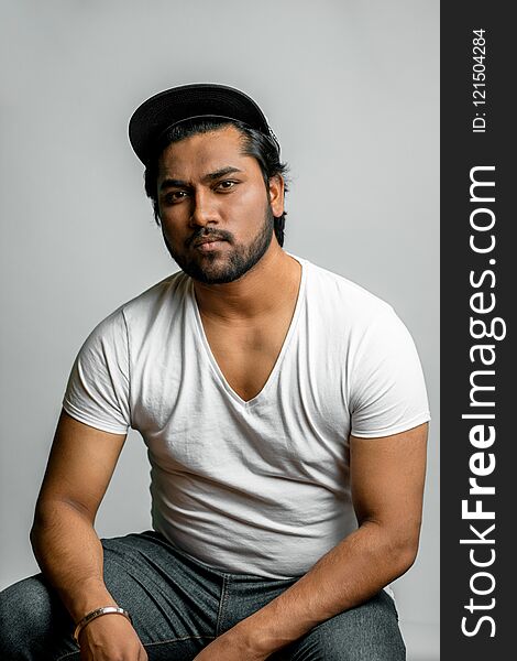 Close up photo of Hindu muscular man in fashion clothes isolated on the white background. indian rapper