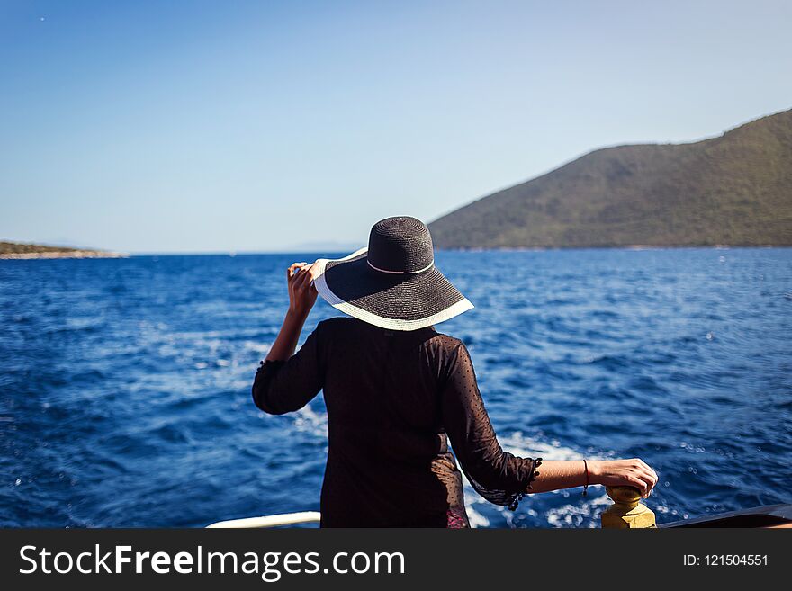 Beautiful girl in hat relaxing on the boat and looking at the island. Travelling vocation tour in Turkey