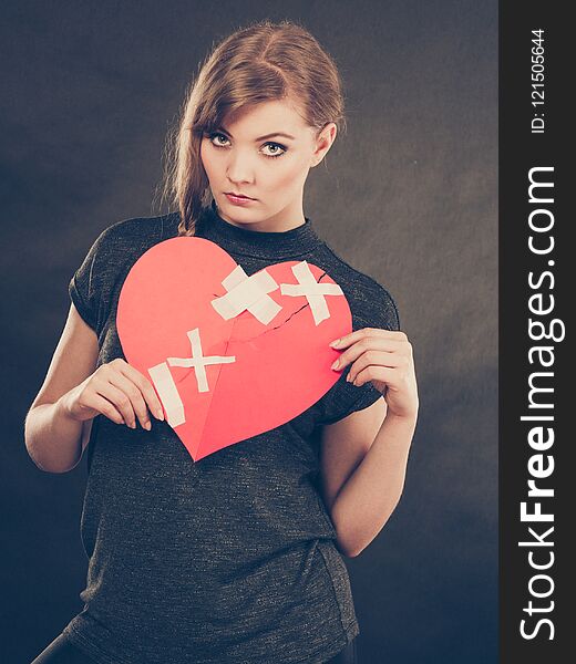 Heart broken concept. Sad unhappy blonde woman with big red love sign symbol glued by plaster. Girlfriend in valentines day. Filtered. Heart broken concept. Sad unhappy blonde woman with big red love sign symbol glued by plaster. Girlfriend in valentines day. Filtered.