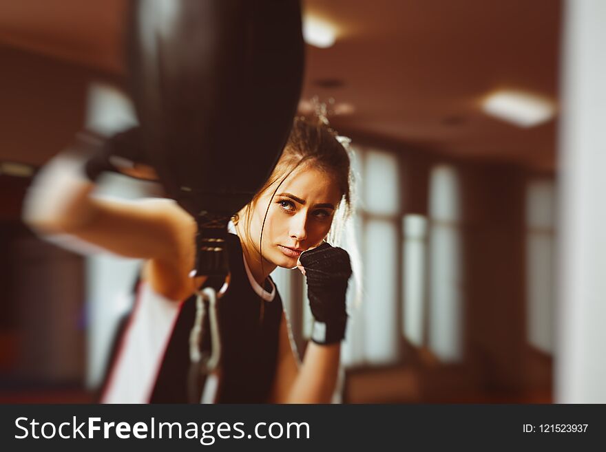 Woman with black boxing wraps on hands boxing in ring. Active girl fight. Right hook with motion blur