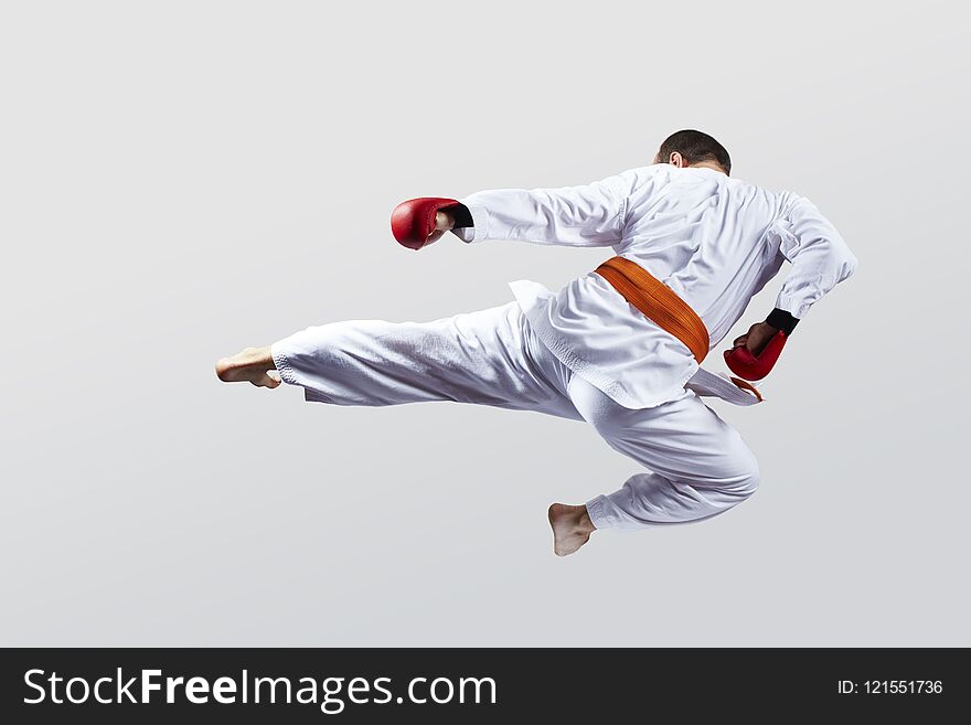 Man with red overlays on his hands trains a kick on a light background