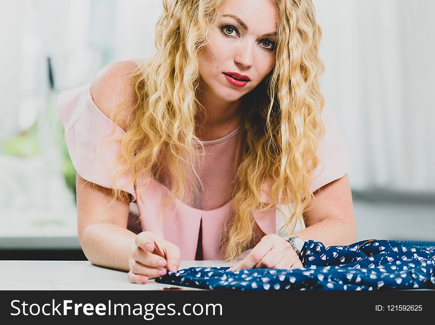 Portrait of young woman working at tailors table in atelier. Portrait of young woman working at tailors table in atelier