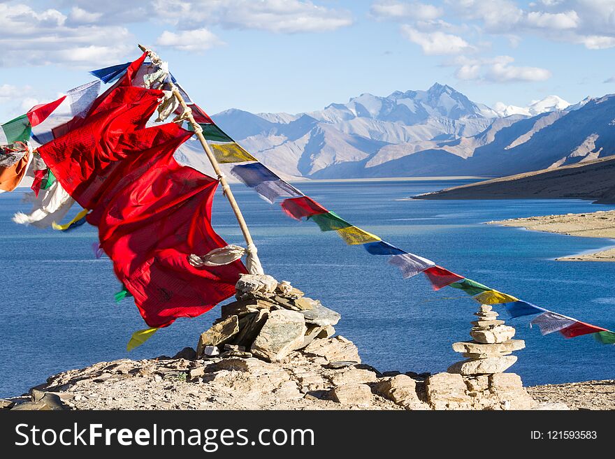 Buddhist prayer flags on the wind against the blue lake, mountains and sky