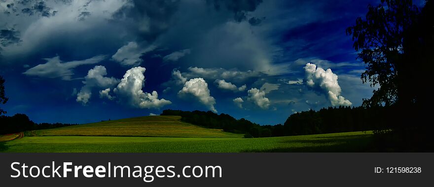 Scenic landscape with storm cloud in background over green agriculture fields,tree and meadows at spring daylight. Dramatic storm clouds and sky.Relaxing nature,sushine. Panoramic photo. Czech Repulic, Europe. .