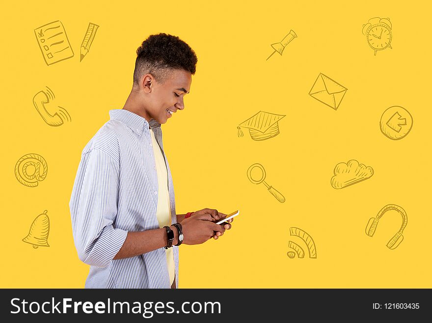 Typing messages. Cheerful popular blogger looking at the screen of his smartphone and smiling while writing messages to his followers. Typing messages. Cheerful popular blogger looking at the screen of his smartphone and smiling while writing messages to his followers