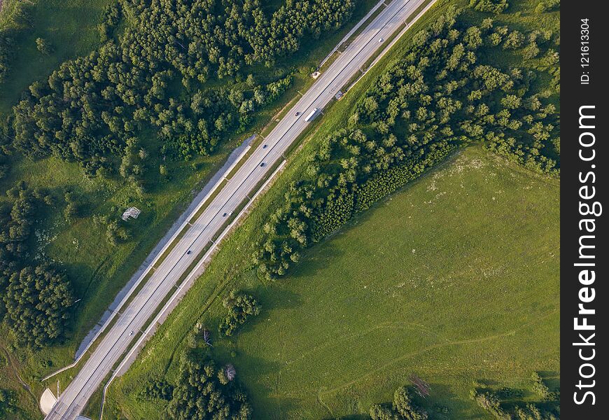 Helicopter drone shot. Aerial photography of green forest with road, green grass. Helicopter drone shot. Aerial photography of green forest with road, green grass.