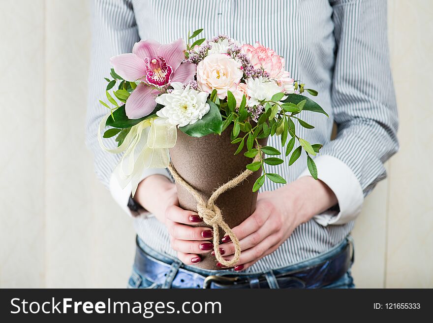 Flower arrangement in a box-cone with fresh flowers in female hands close-up