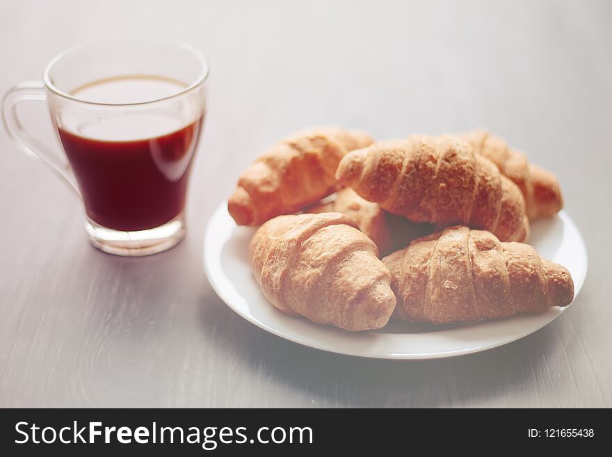 Coffee cup and fresh baked croissants on wooden background. Top View. Coffee cup and fresh baked croissants on wooden background. Top View.