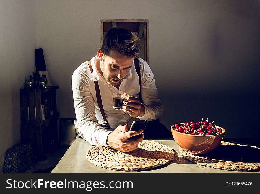 Man looking at his cell phone and drinking coffee