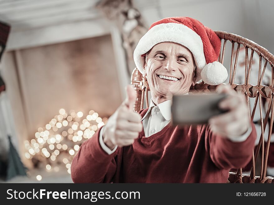 Video call. Happy male keeping smile on his face and stretching hand while looking at camera. Video call. Happy male keeping smile on his face and stretching hand while looking at camera