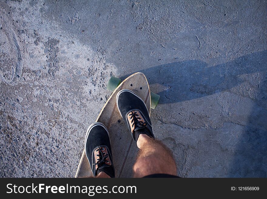 Skater in red shirt and blue jeans riding near beach on longboard during sunrise, sea or ocean background. Skater in red shirt and blue jeans riding near beach on longboard during sunrise, sea or ocean background