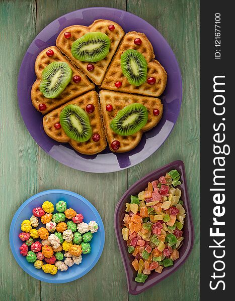 Wafers with kiwi and cranberries on a wooden background. waffles on a plate top view