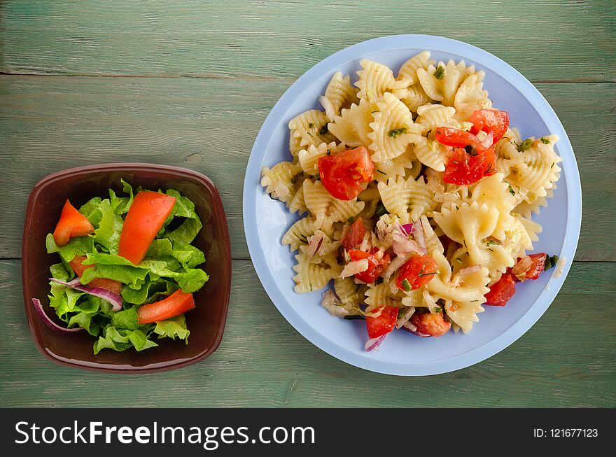 Pasta on a plate. pasta tomatoes, onions, cabbage on a wooden background