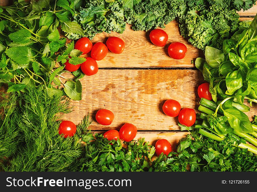 Green vegetable herbs and tomatoes on a wooden table