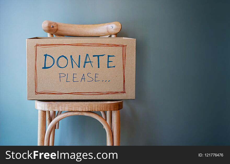 Donation Concept. Empty Donate Box on Chair against Wall in Public Space