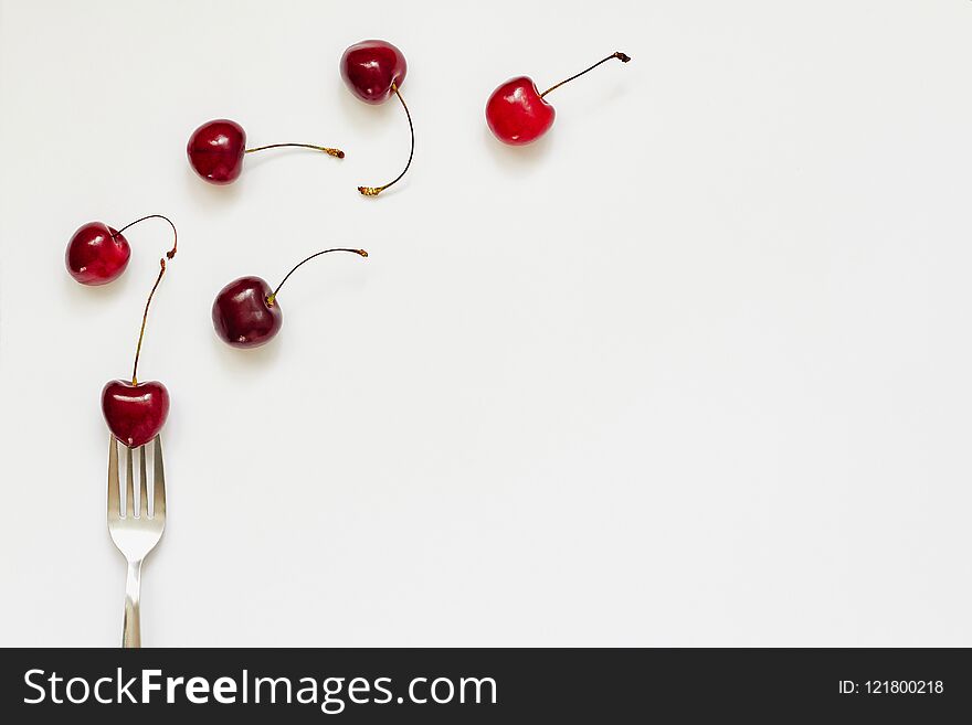 Red cherry fruits and fork on white background with copy space for text. Summer, diet, healthy food eating consept. Top view, flat lay, layout, pattern