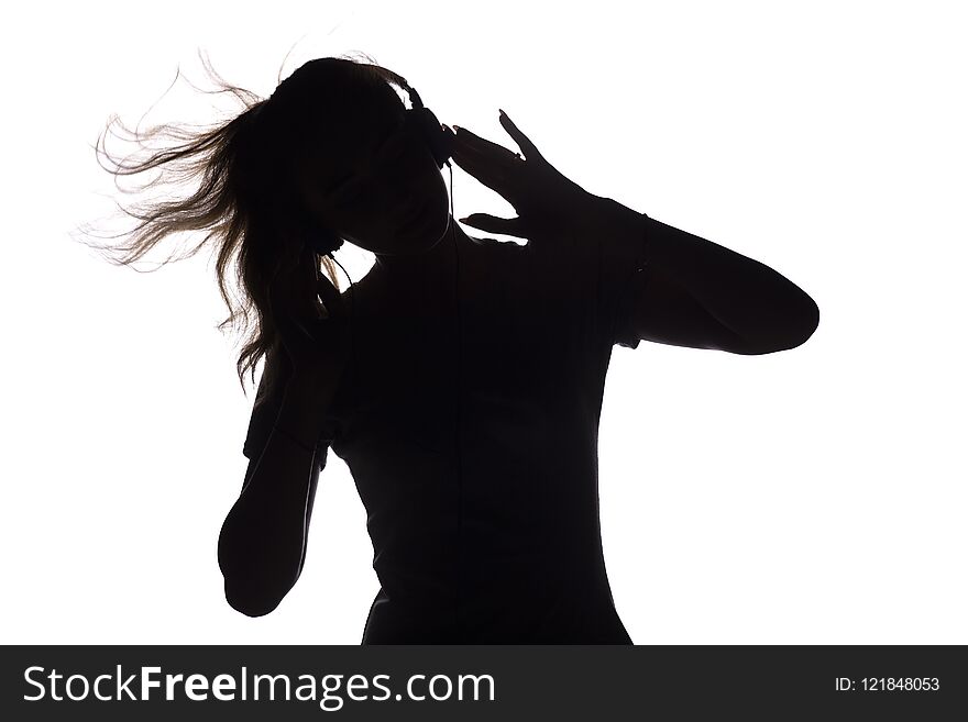 Silhouette of a girl listening to music in headphones, young woman relaxing on a white isolated background, concept of hobby and leisure. Silhouette of a girl listening to music in headphones, young woman relaxing on a white isolated background, concept of hobby and leisure