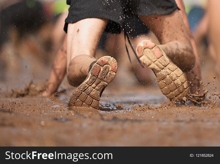 Mud race runners.Crawling,passing under a barbed wire obstacles during extreme obstacle race