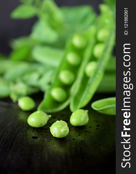 Green pea pods against the dark background