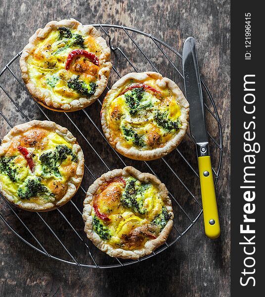 Broccoli cheddar mini savory pies on wooden background, top view. Delicious appetizers, snack, tapas. Flat lay, copy space