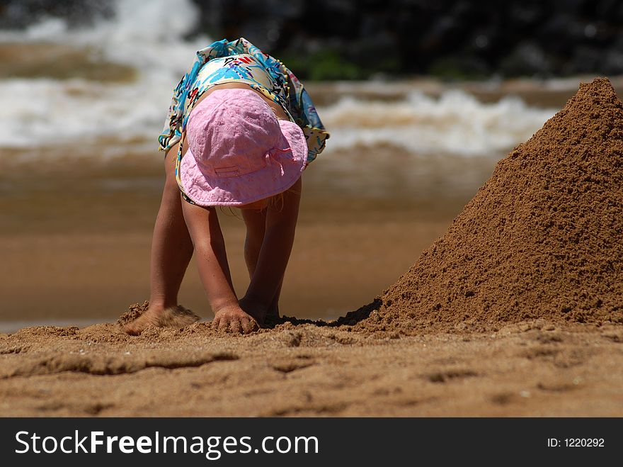 A small girl is building a sand tower. A small girl is building a sand tower