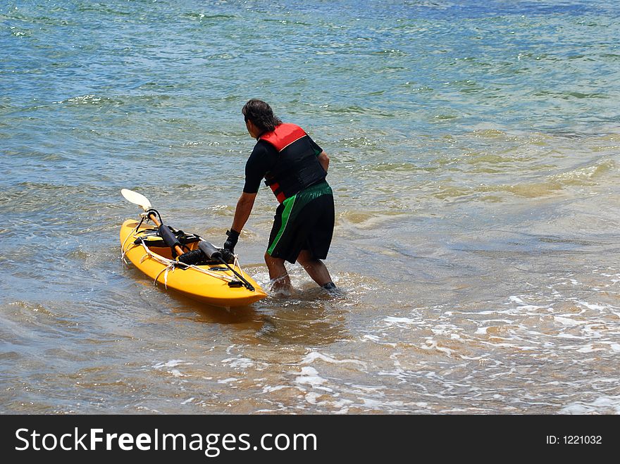 A man with kayaki boat going into the water. A man with kayaki boat going into the water