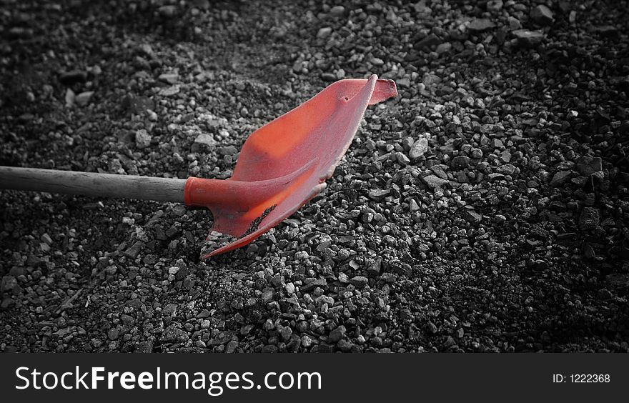 Old, broken red shovel in gravel