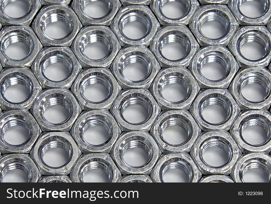Zinc plated hex nuts arranged in a pattern.