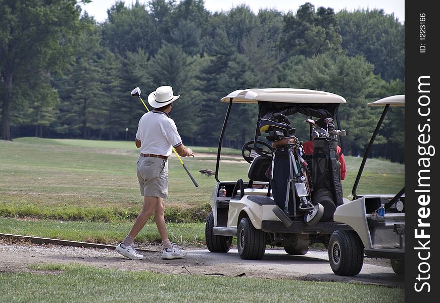 Senior golfer with large brimmed hat on the links.