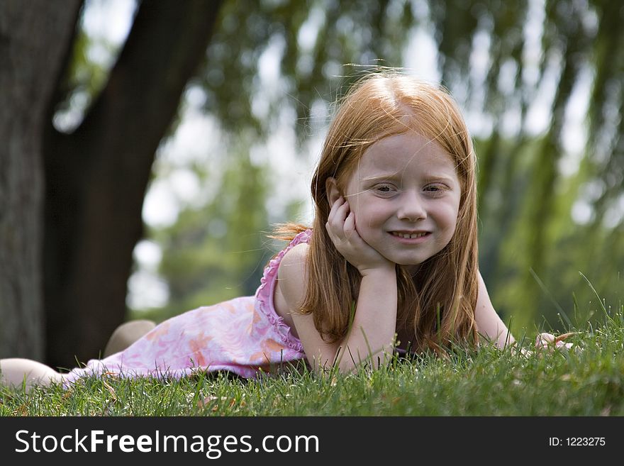 Small redheaded girl laying in grass contemplating the world around her. Small redheaded girl laying in grass contemplating the world around her.