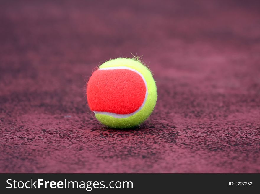 Yellow and orange tennis ball on the ground