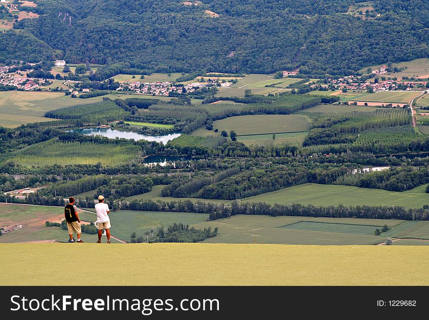 Two men standing on the edge of a cliff with the valley below