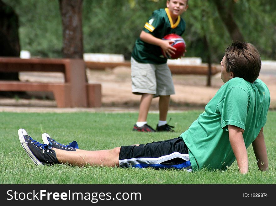 Boy resting on the grass after playing soccer.