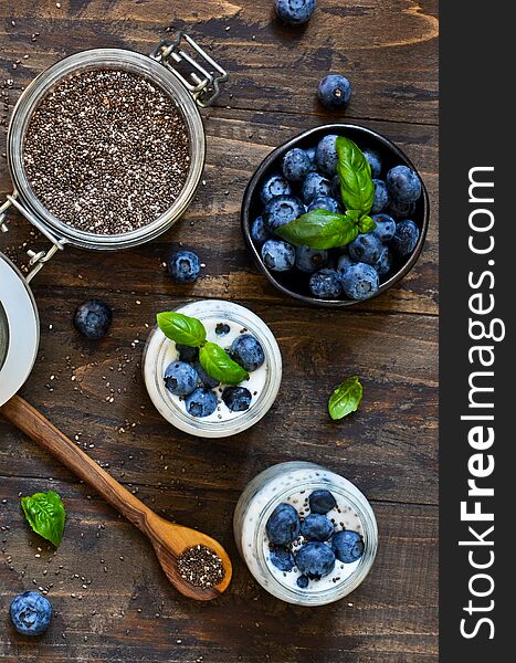 Homemade yogurt with sesena chia and blueberries that have a dark background.